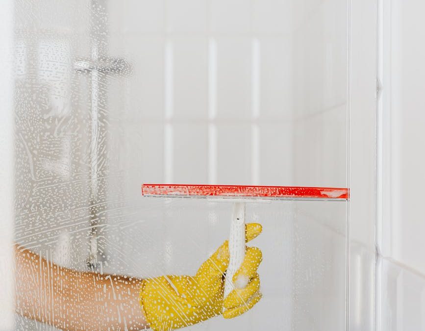 crop person cleaning glass shower unit